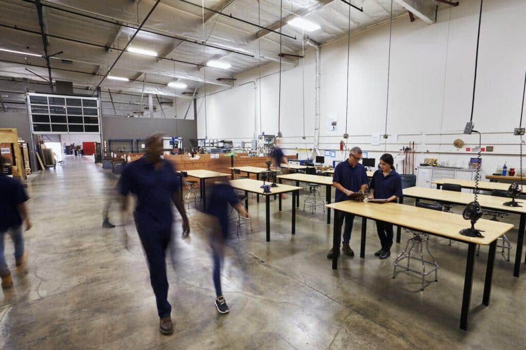 Interior Of Busy Factory With Staff At Work Benches